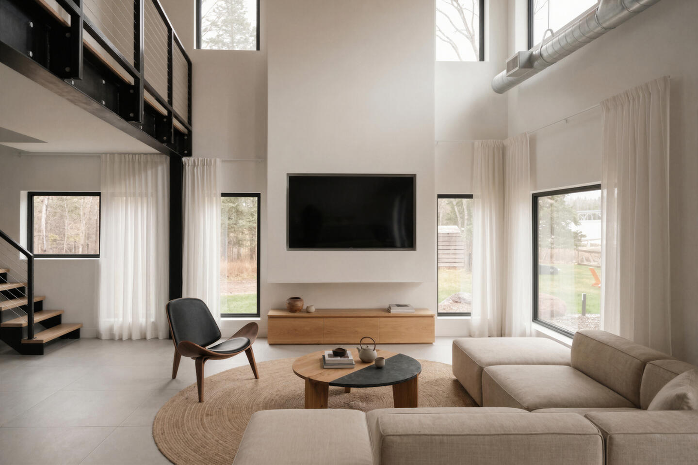 Modern minimalist living room of a cabin with double-height ceilings, neutral sectional sofa, wood TV console, and floor-to-ceiling windows
